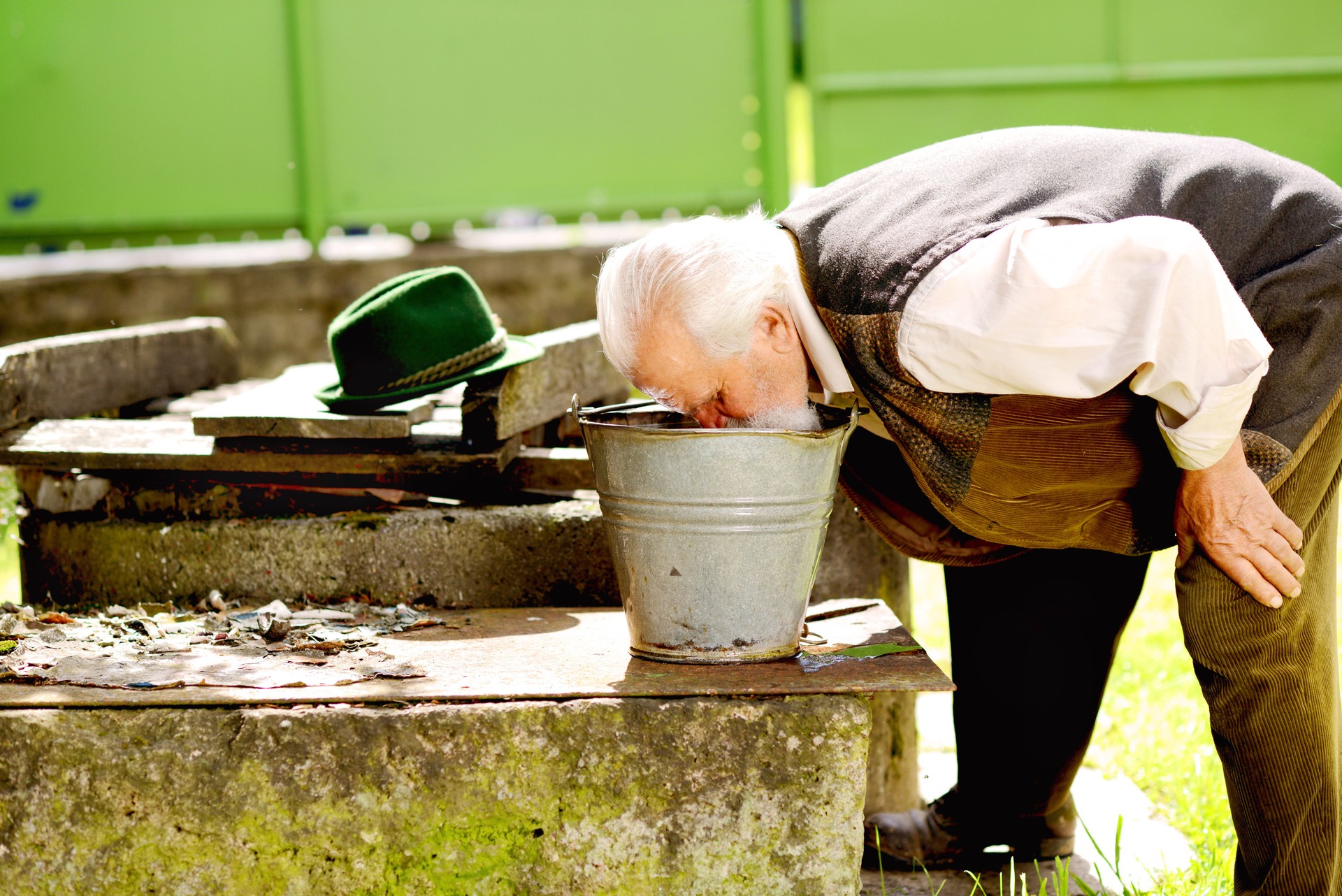 Old farmer trinkt aus wassereimer, unhygienisches wasser, dreckiges wasser in deutschland 